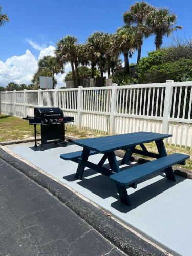 a picnic table and a grill next to a fence at Sugar Sands - Ocean front at Symphony Beach Club ! in Ormond Beach