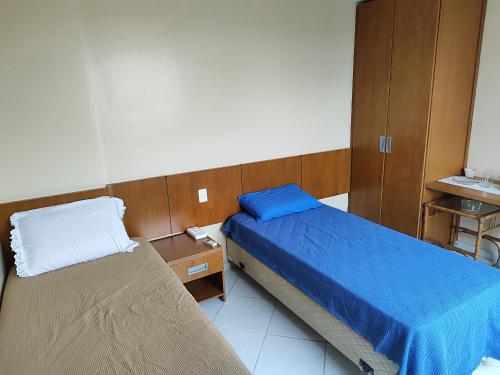 a room with two beds and a night stand with a bed sidx sidx at Suíte Funcional Independente - Via Park Flat Service - Campos dos Goytacazes in Campos dos Goytacazes