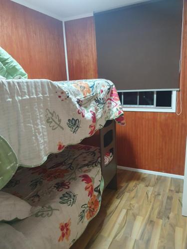 ein Schlafzimmer mit einem Bett mit einer Decke und einem Fenster in der Unterkunft Casa en Peñuelas in Coquimbo