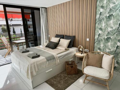 a bedroom with a bed and a chair at Olympia Palmalicious Apartment in Playa de las Americas