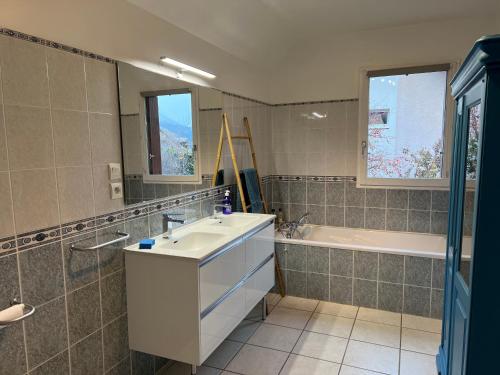 a bathroom with a sink and a tub and a mirror at MAISON DES VIGNES in Embrun