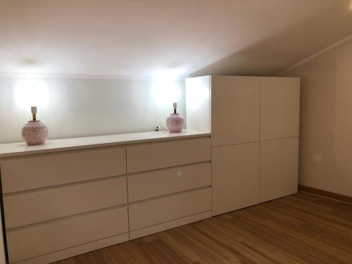 a white kitchen with two vases sitting on a shelf at Pool oasis with private parking -Vigia 8 in Torres Vedras