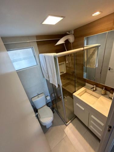 uma casa de banho com um WC e uma cabina de duche em vidro. em Meu aconchego em Maceió - 2qts com ar e 1 vaga de garagem em Maceió