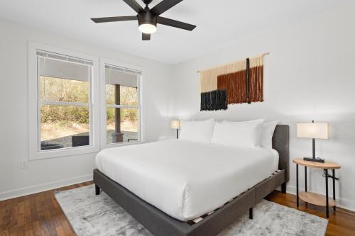 a white bedroom with a bed and two windows at Sage Lodge by AvantStay 15 Min to Downtown Deck in Asheville