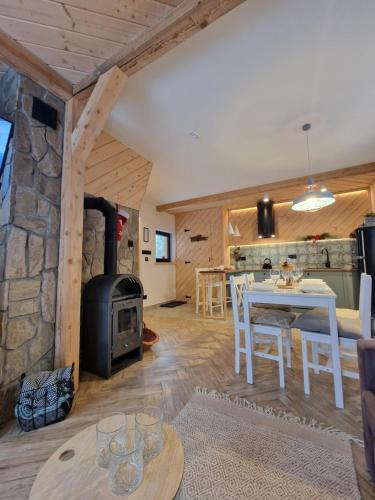 un salon avec une cheminée en pierre et une table et des chaises dans l'établissement FILIPOWE CHATY, à Kościelisko