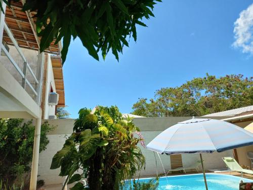 a blue and white umbrella next to a swimming pool at Pousada Cajueiro in Itaúnas