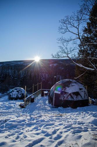 two tents in the snow with the sun in the background at BUNNY GLAMP in Korbielów
