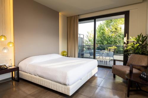 a bedroom with a white bed and a balcony at Ananti Resort & Spa in Tríkala