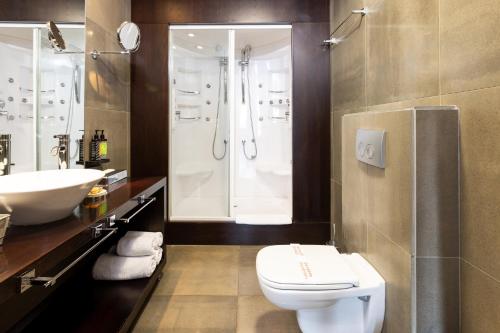 a bathroom with a toilet and a shower and a sink at Ananti Resort & Spa in Tríkala