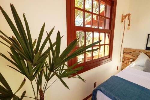 a bedroom with a plant next to a window at Casa Örüm in Florianópolis