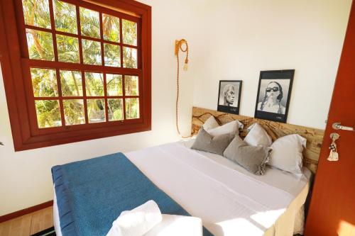 a bedroom with a large white bed with a window at Casa Örüm in Florianópolis