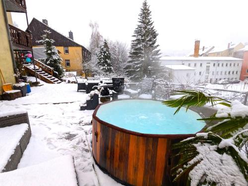 una bañera de hidromasaje cubierta de nieve en un patio en Urlaubsmagie - Helle Wohnung mit Sauna & Pool & Whirlpool - F1, en Sebnitz