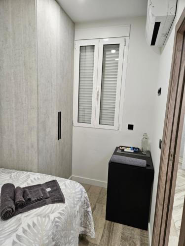 um pequeno quarto com uma cama e uma janela em Habitación céntrica de Lujo Gv 4 em Valência