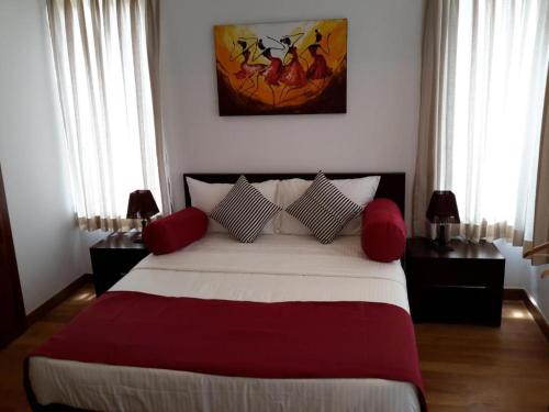 a bedroom with a large bed with red pillows at Nilaveli Ocean Front Condos 1G1 in Nilaveli