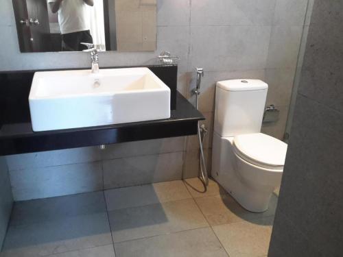 a bathroom with a white sink and a toilet at Nilaveli Ocean Front Condos 1G1 in Nilaveli
