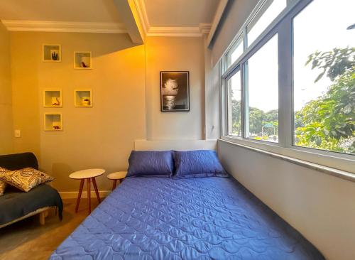 Bett in einem Zimmer mit einem großen Fenster in der Unterkunft Otimo apto a poucos metros da Praia de Botafogo RJ in Rio de Janeiro