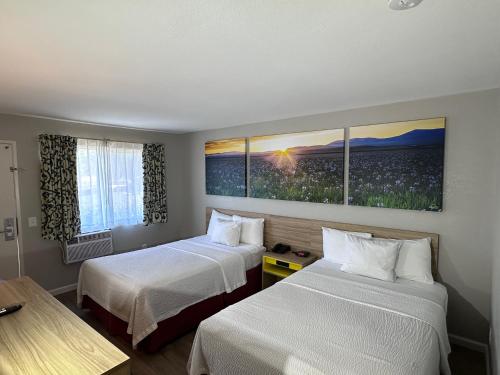 a hotel room with two beds and two windows at Days Inn by Wyndham San Marcos in San Marcos