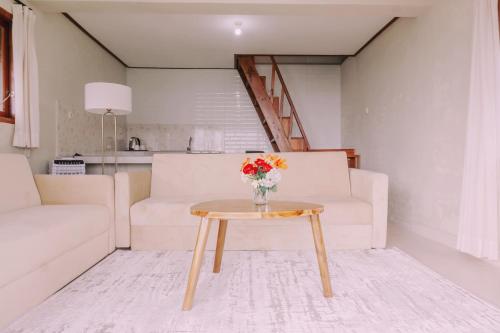 a living room with a table with a vase of flowers on it at Camaradvipa Retreat Munduk in Munduk