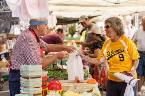 a man handing a woman a bag at a market at The Brownwood Hotel & Spa in The Villages