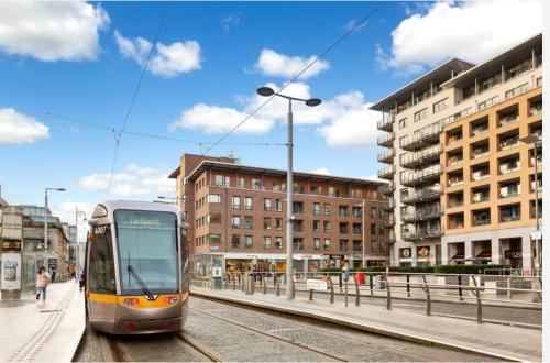 a train on the tracks in a city with buildings at IFSC Room in Dublin