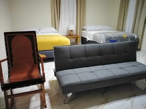 a couch and a chair in a room with two beds at Baruch Tropical Ranch in Los Santos
