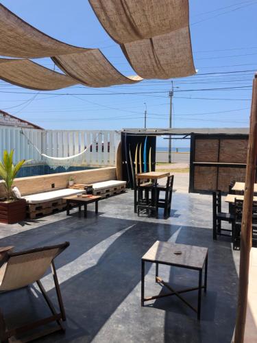 a patio with tables and chairs and a surfboard at Pointbreak Surf Camp in Huanchaco