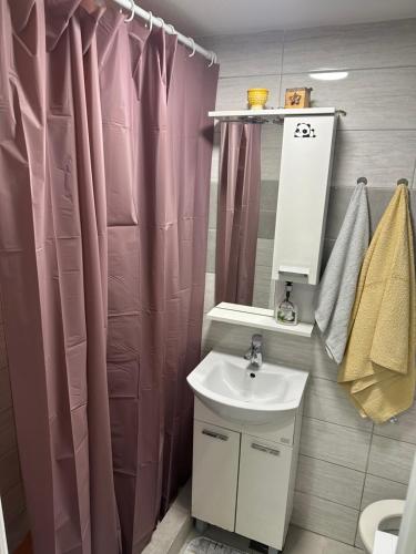 baño con lavabo y cortina de ducha rosa en MG Sa, en Sarajevo