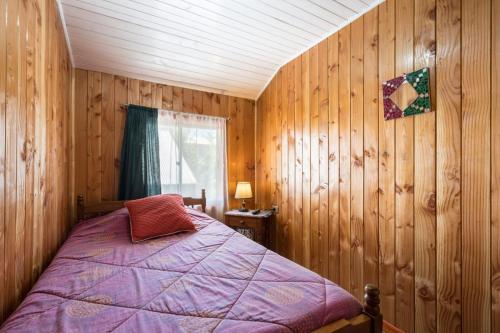 1 dormitorio con 1 cama en una habitación de madera en Hospedaje Isla Talcan, en Dalcahue