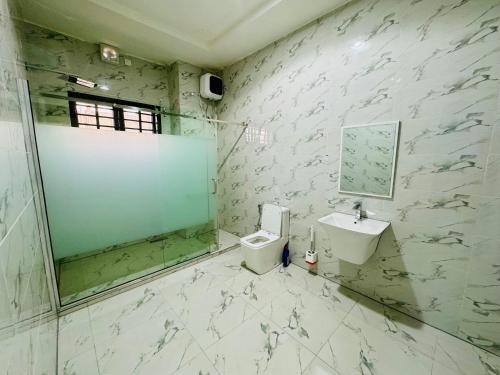 a bathroom with a shower and a toilet and a sink at Luxury Villa within Abuja Sanctuary in Abuja