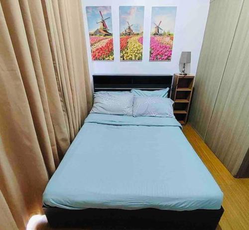 a bed in a room with two paintings on the wall at LD Cozy 1BR Grace Residences, Taguig near BGC in Manila