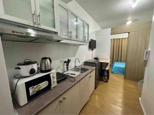 a kitchen with a sink and a stove top oven at LD Cozy 1BR Grace Residences, Taguig near BGC in Manila