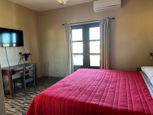 1 dormitorio con cama roja, escritorio y ventana en Chulavista Loreto, en Loreto