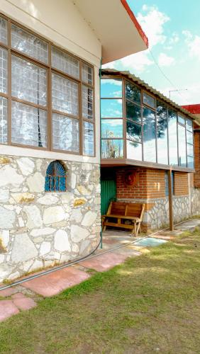 a house with a bench on the side of it at Cabañas- Casas España in Mineral del Chico