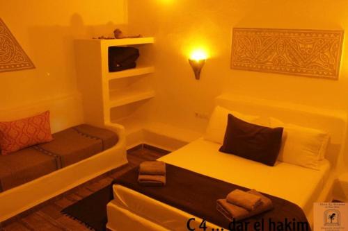 Habitación pequeña con cama y sofá en Dar El Hakim, le petit hôtel de Timimoun en Timmoun
