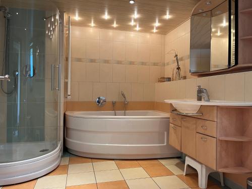 a bathroom with a tub and a shower and a sink at Ferienhaus Auszeit Harz Braunlage/Hohegeiß in Braunlage