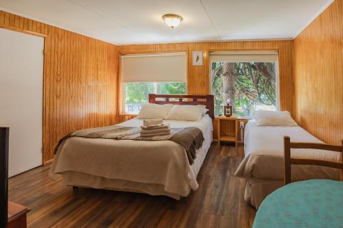 a bedroom with two beds and a desk and a window at Hostal Viento Sur in Coihaique