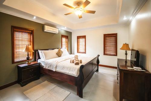 a bedroom with a bed with a ceiling fan and a desk at Bram Villa in Canaan