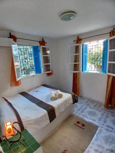 a bedroom with a bed and two windows at Menzel Churasco Djerba in Aghīr