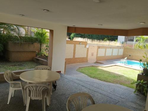 un patio con mesa, sillas y piscina en Tu_refugio_playero en Caraballeda