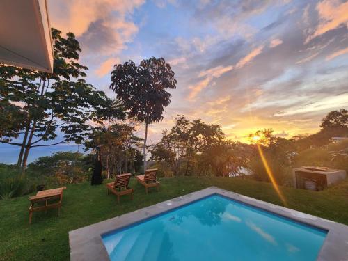 a backyard with a pool and chairs and a sunset at Canavida Villas & Resort in Uvita