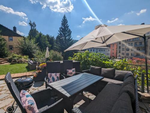 a patio with a table and an umbrella at HW3 - Urlaubsmagie - Helle, große Wohnung mit Pool in Sebnitz