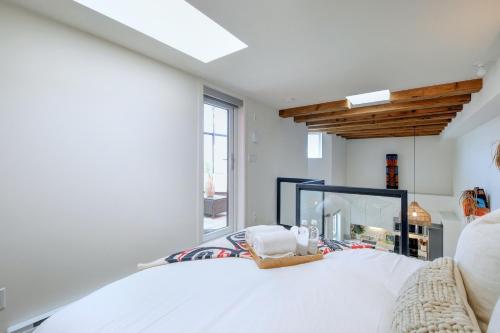 1 dormitorio con cama blanca y ventana grande en West Coast Loft with Rooftop Patio + Harbour View, en Victoria
