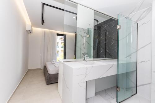 a bathroom with a sink and a glass shower at Varkiza Luxury Suites in Vari