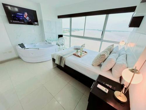 a bedroom with a bed and a tub and a television at Ecusuites Ejecutiva Mini view río guayas Aeropuerto in Guayaquil