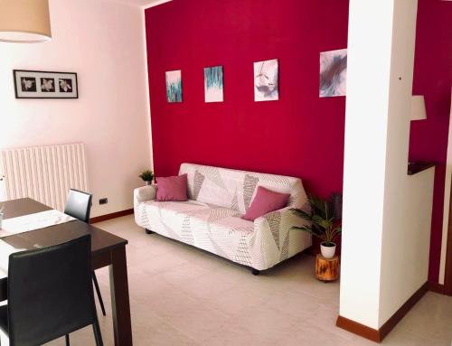 sala de estar con sofá blanco y pared roja en la Dolce Vita - Appartamento con parcheggio privato vicino al centro e all'ospedale, en Asti