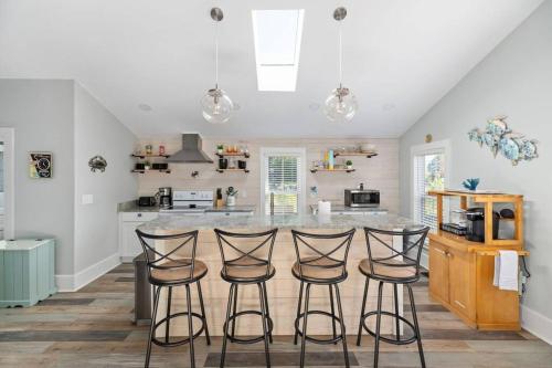 a kitchen with a counter with four bar stools at The Lyellton House: Water View, Steps from Beach in Colonial Beach