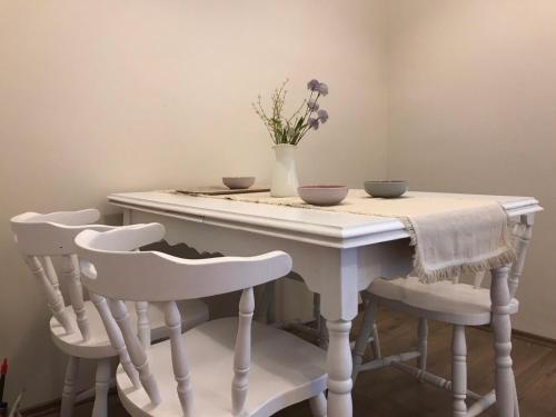 a table with three chairs and a vase with flowers on it at S2 Apartman in Kaposvár
