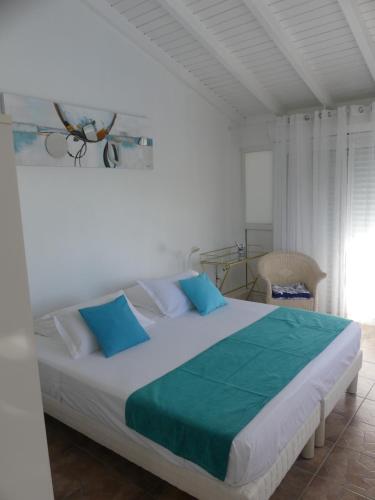 een slaapkamer met een groot bed met blauwe kussens bij Villa Magnifique piscine & jardin in Baie-Mahault