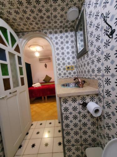 een badkamer met een wastafel en een kamer met een bed bij Honey Suckle in Chefchaouene