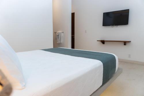 a bedroom with a bed and a tv on a wall at Kanté Hotel - Downtown Tulum in Tulum